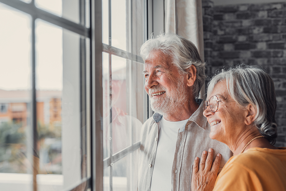 A retired couple looking out the window of their home thinking about the importance of estate planning.