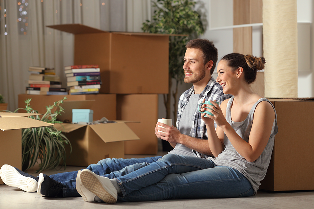 A couple sitting by unpacked boxes in a new house. Your Mortgage Tailored for You.