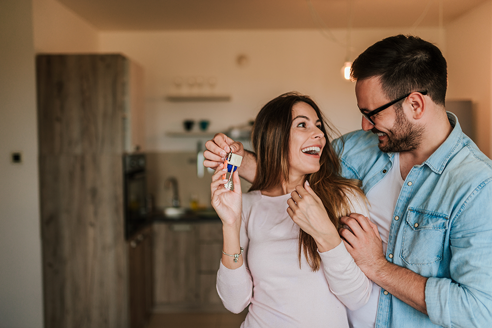 A couple in a new house holding the key representing opportunities for Co-op and Co-ownership housing.