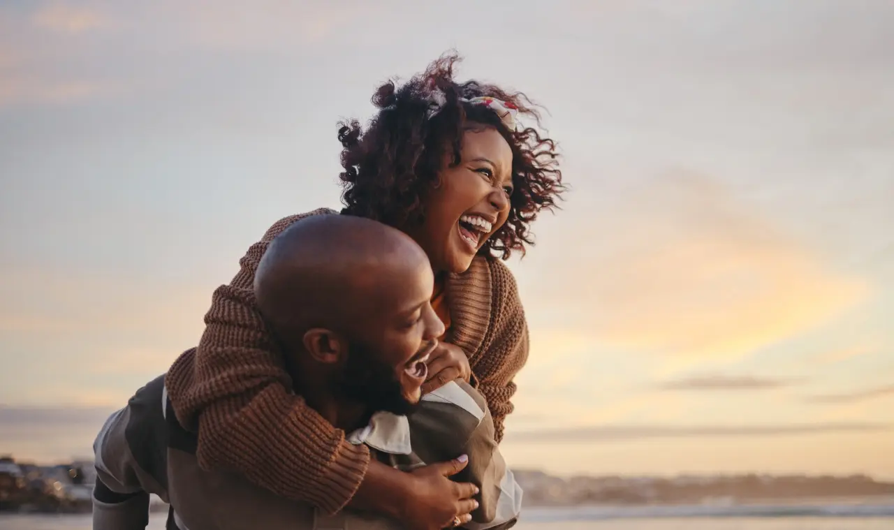 A couple smiling with their backs to the sunrise